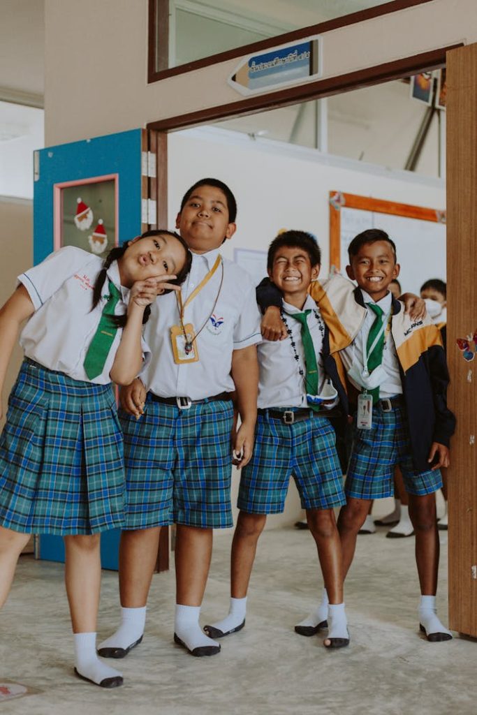 Happy group of students in school uniforms standing together in a classroom setting.