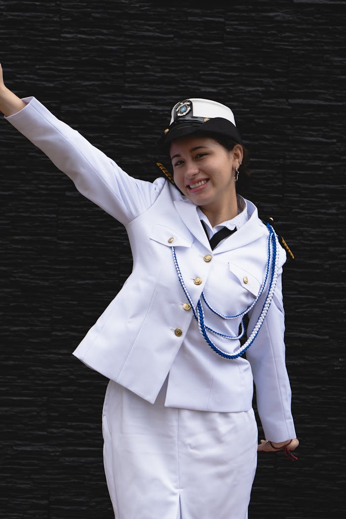 Portrait of a smiling woman in a white military uniform against a black background.