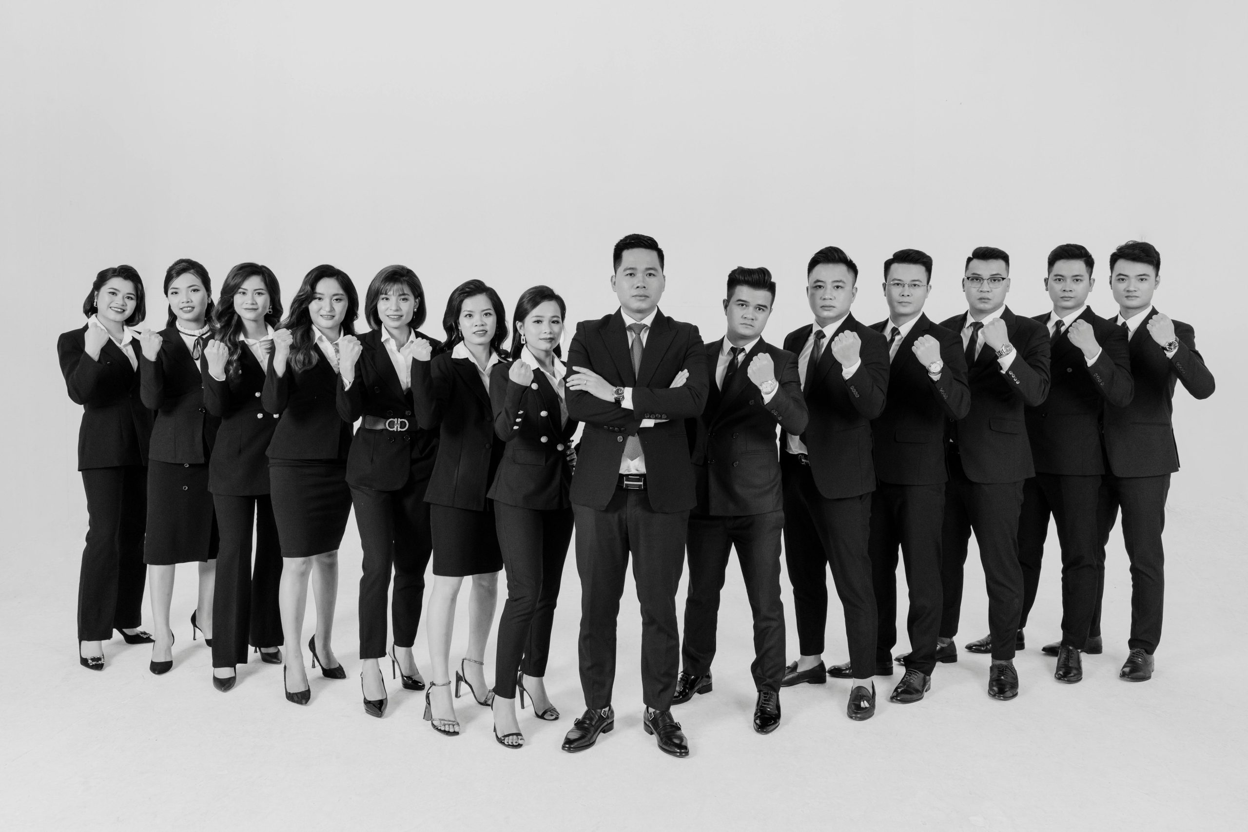 Black and white portrait of a confident, diverse corporate team in formal attire in a studio setting.