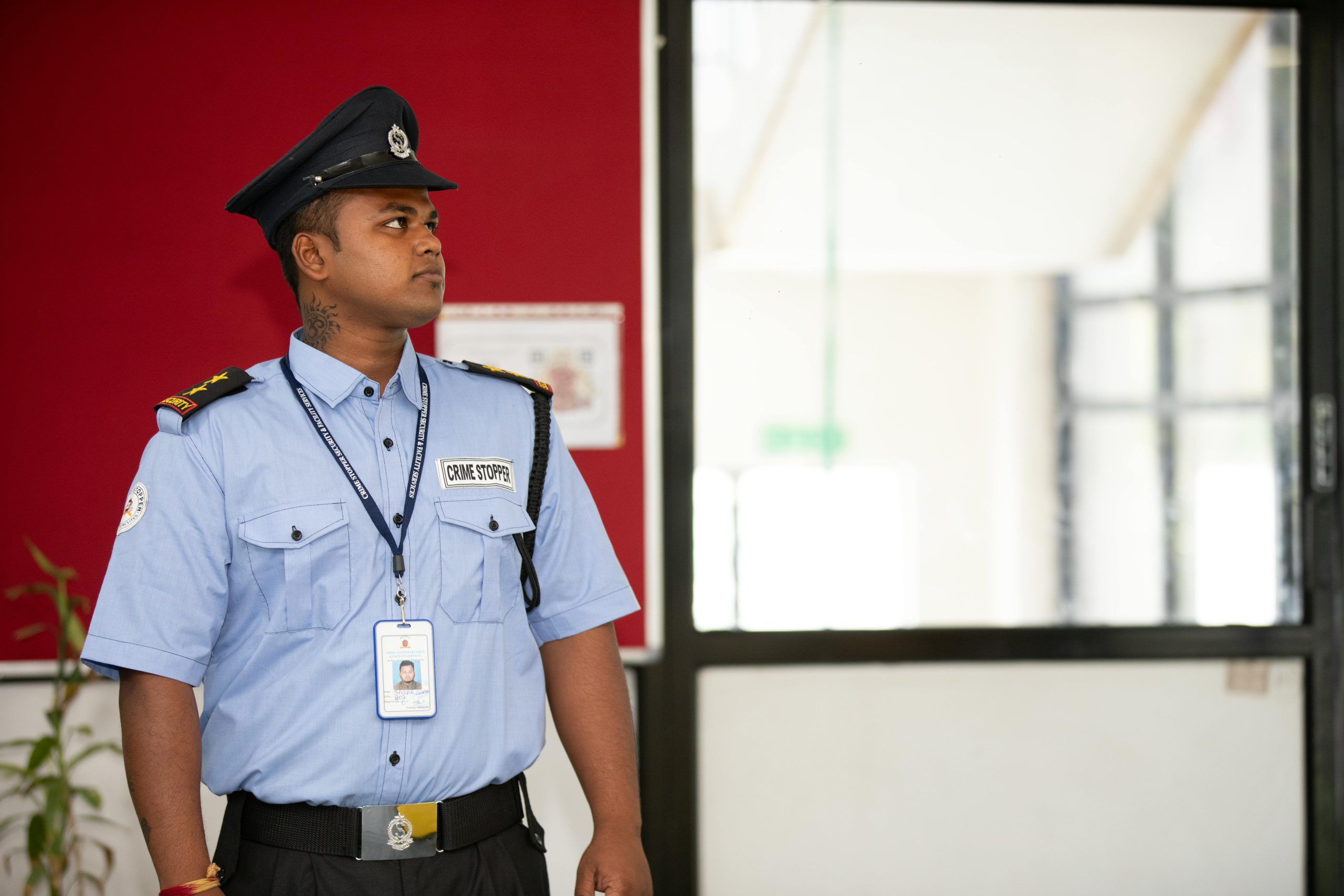 Security guard in uniform standing alert at a building entrance.