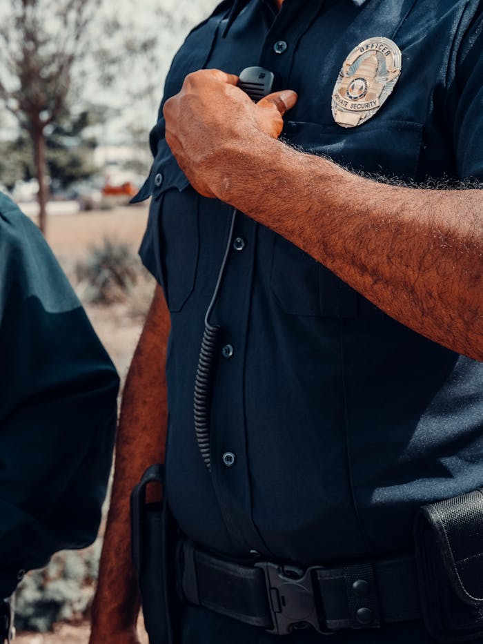 A close-up image of a police officer adjusting a radio outdoors.